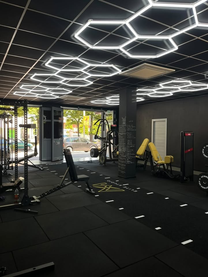 Sala di NM Élite Studio vista dall'ingresso, con rack, panche e vetrata sulla strada
